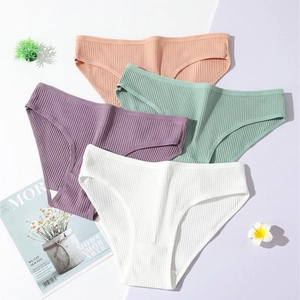 Flat lay of four cotton ribbed low-waist panties in pastel shades on minimalist backdrop