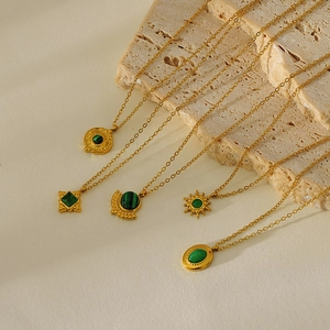 Vintage gold necklaces with green turquoise and malachite pendants on stone background