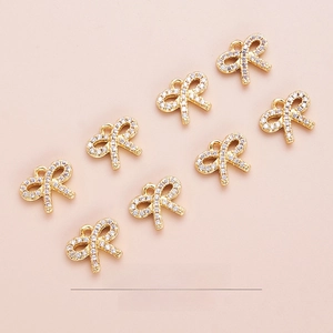 Detailed view of 10mm gold bow pendants set with white zircon for DIY jewelry making