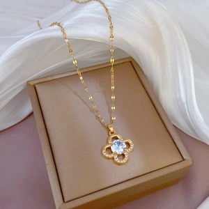 Elegant gold clover necklace with zircon pendant displayed on a luxury jewelry box