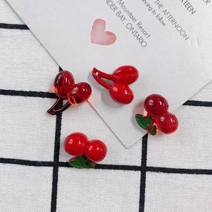 Detail of red acrylic cherry pendants for DIY jewelry making on checkered fabric