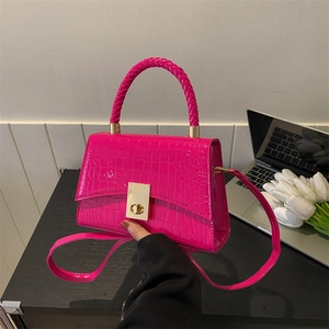 Hot pink faux crocodile leather handbag with woven handle and gold hardware in hand