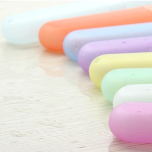 Portable candy-colored travel toothbrush cases in a multi-color set on a wet surface