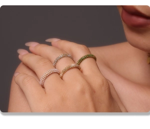 Close-up of four minimalist stacking rings with pearls, white and green zircons
