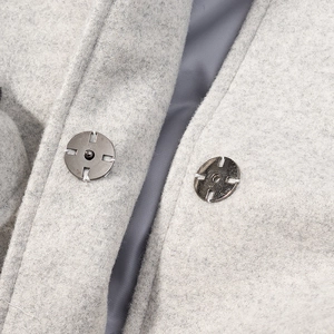 Dettaglio macro di cappotto in lana grigio chiaro con bottoni automatici in metallo