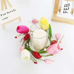 Detail of tulip candle ring with pink berries and heart charms on a white table