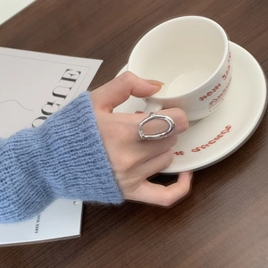 Close-up of irregular 925 sterling silver ring worn while holding a white coffee cup