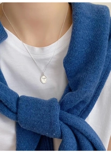 Close-up of a 925 sterling silver oval pendant with an engraved smile face on a necklace