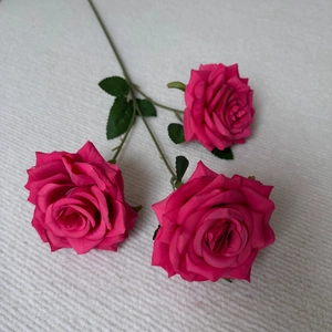 Detailed overhead view of three vibrant rose pink artificial roses with realistic silk petals