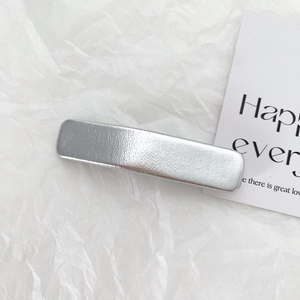 Detailed view of silver metallic matte hair clip on decorative white textured paper