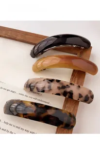 Macro shot of minimalist acrylic spring hair clips in four elegant tortoiseshell colors