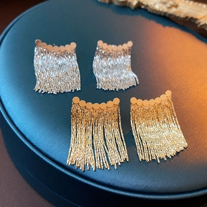 Detailed view of silver and gold chain tassel earrings on a vintage display stand