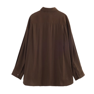 Detail view of brown loose fit long sleeve shirt showing curved hem and smooth texture