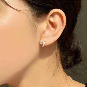 Detailed view of silver bow-shaped stud earring with textured rope pattern on ear lobe