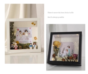 Detail of shadow box frame with dried flowers, LEGO style figures, and warm LED lights