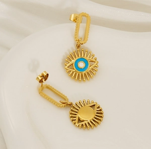 Detailed view of gold evil eye drop earrings with blue enamel on a ceramic tray