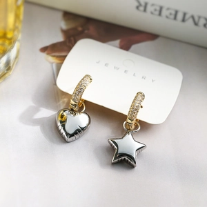Detail of silver heart and star asymmetrical earrings on jewelry card with gold cubic zirconia hoops