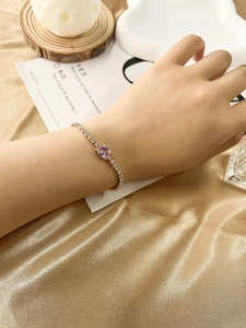 Detailed shot of a gold bracelet featuring a pink oval zircon stone on a model's wrist