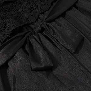 Dettaglio ricamo in pizzo nero e tessuto metallizzato con fiocco decorativo elegante