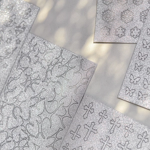 Macro shot of silver glitter nail art stickers featuring butterfly and star hollow designs