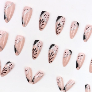 Almond-shaped press-on nails with black leaf art and pink glitter finish on white background