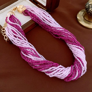 Close-up of multilayer beaded necklace with pink beads and golden flower petal clasps