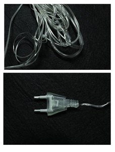 Close-up of LED curtain lights with transparent wires and a standard EU power plug