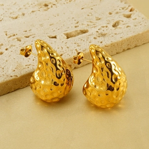 18K gold teardrop earrings with hammered texture on a textured stone and silk background