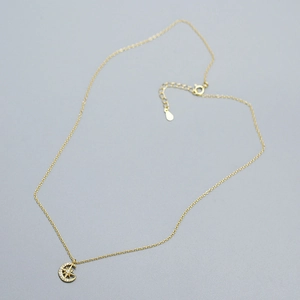 Macro shot of gold star and crescent moon pendant with sparkling cubic zirconia on fine chain