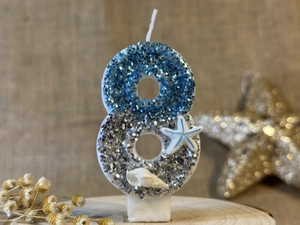 Close-up of number 8 ocean themed birthday candle with blue silver sequins and seashells