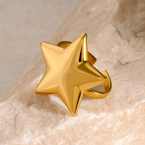 Close-up of golden star-shaped open ring on natural stone showing metallic texture