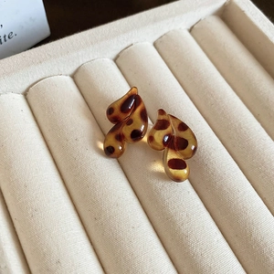 Close-up of leopard print resin earrings in a velvet jewelry box with soft lighting