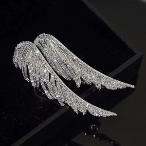 Macro di una spilla ad ala d'angelo argentata con strass scintillanti su superficie scura