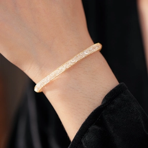 Vue macro d'un bracelet en maille dorée rempli de cristaux sur le poignet d'un modèle