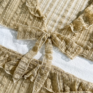 Detail of beige lace bikini set with delicate floral embroidery and front tie bow design