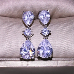 Elegant silver teardrop zircon earrings in three-tier dangle design on champagne satin