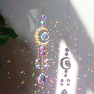 Golden moon crystal suncatcher hanging against a white wall with rainbow light reflections