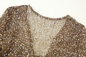 Détails de la maille dorée et paillettes argentées sur la robe à col en V chic