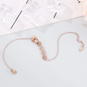 Detail of rose gold stainless steel anklet with ancient coin and bell charms