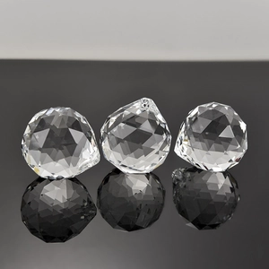Three faceted clear crystal lighting spheres with hanging holes on reflective surface