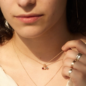 Close-up of 18K gold birthstone necklace with red, white and blue zircon pendants on model