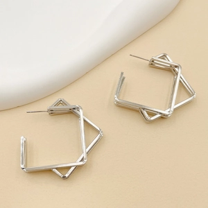 Macro detail of geometric silver earrings with multi-layered square frames and polished finish
