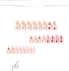 Detail of pink checkerboard press-on nails with smile faces, hearts, and glitter finish
