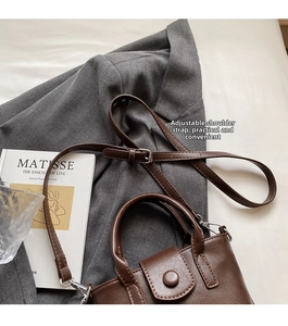 Detail of vintage brown leather bucket bag showing adjustable strap and silver metal buckle