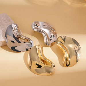 Minimalist metallic irregular wavy stud earrings in gold and silver on stone
