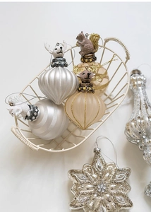 Close-up of champagne and silver glass ornaments with resin animal figures in a wire basket