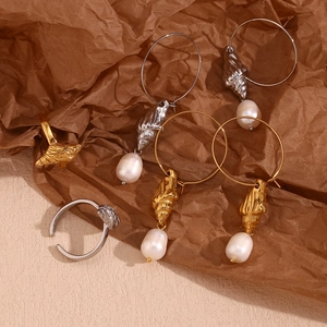 Detailed view of 18K gold plated conch earrings and shell ring with freshwater pearls