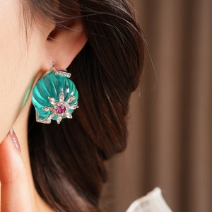 Close-up of vintage flower stud earring with green texture and red center gemstone