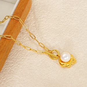 Macro detail of gold bow pearl pendant with toggle clasp on a stylish chain