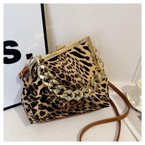 Detail of leopard print shell bag featuring a thick gold chain handle and brown strap